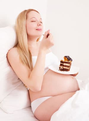 Schwangere mit Heißhunger isst Schokoladenkuchen