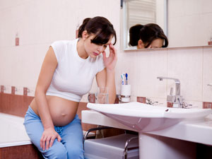 Schwangere Frau mit Morgenübelkeit im Bad