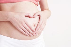 Schwangere Frau die sich wegen Verdauungsbeschwerden den Bauch hält