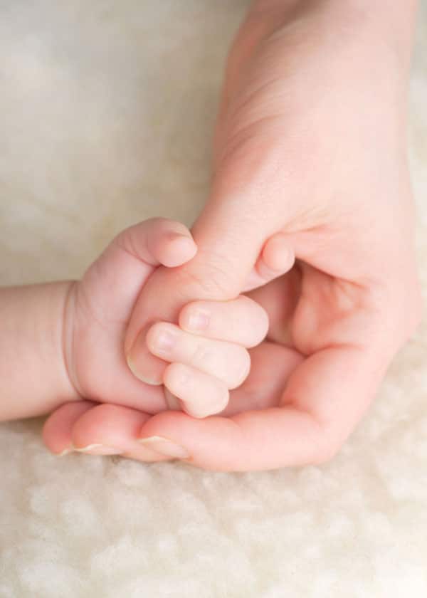 Baby Hand greift nach dem Daumen der Mutter