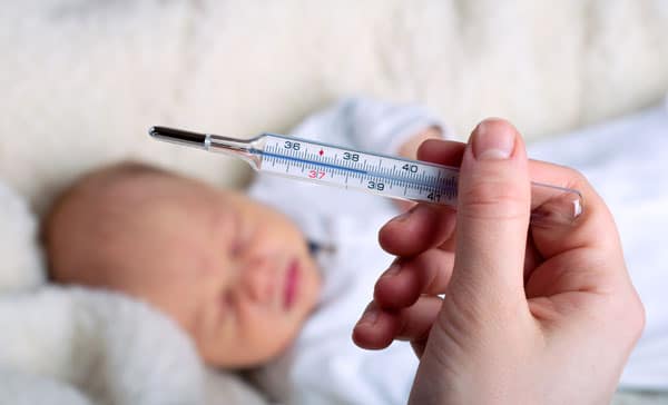 Fieberthermometer mit Baby im Hintergrund