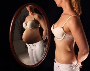 Nicht schwangere Frau sieht sich im Spiegel als schwangere