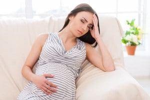 Schwangere Frau hält sich wegen Kopfschmerzen den Kopf