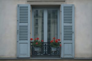Pariser Fenster mit schmiedeeisernem Balkon und roten Geranien