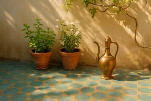 Sonniger Innenhof mit handbemalten Fliesen, Messingkanne und Minze im Topf